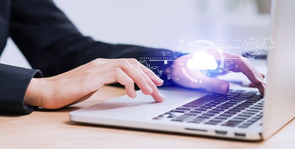 Woman's hand controls a laptop with cloud graphic overlayed.