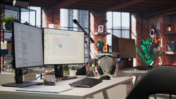 Dual monitor PC on a desk in a modern office.