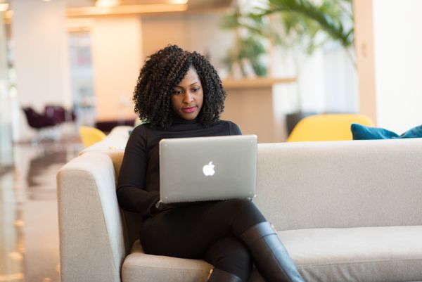 Woman sat on an office couch working on a laptop